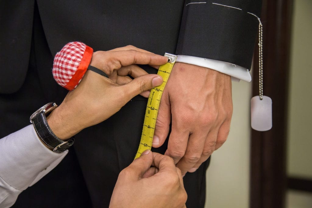 Custom tailor measuring a suit and shirt sleeve
