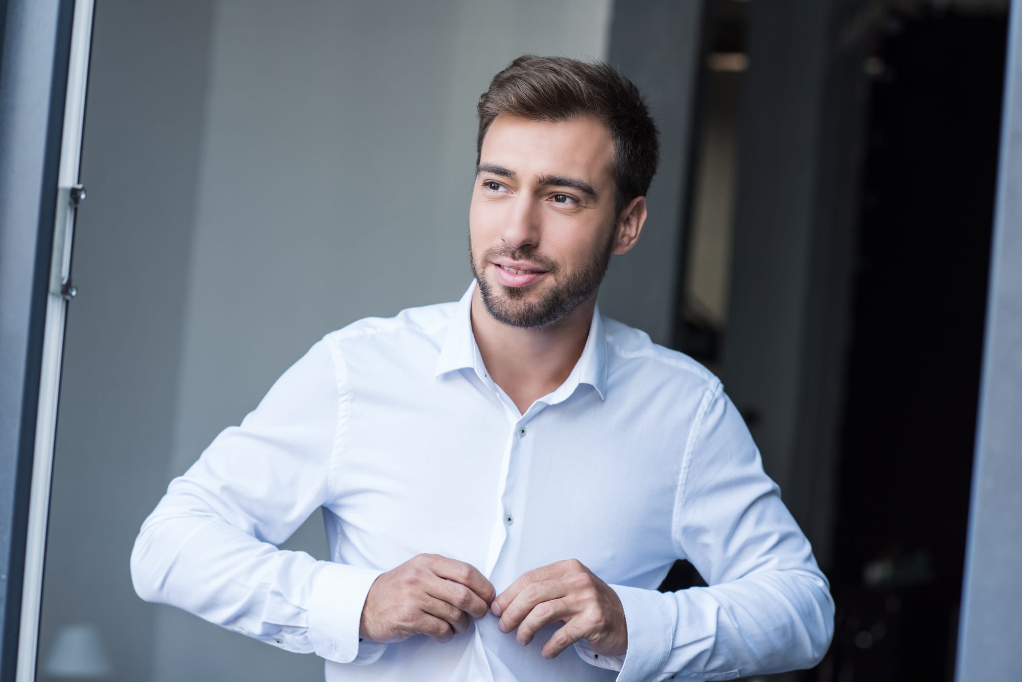 Man buttoning up dress shirt to get the perfect fit