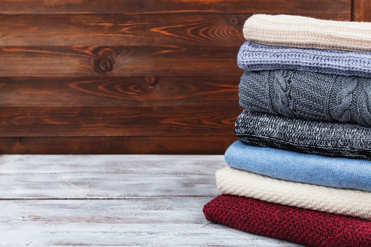 stack-of-sweaters-on-wooden-background