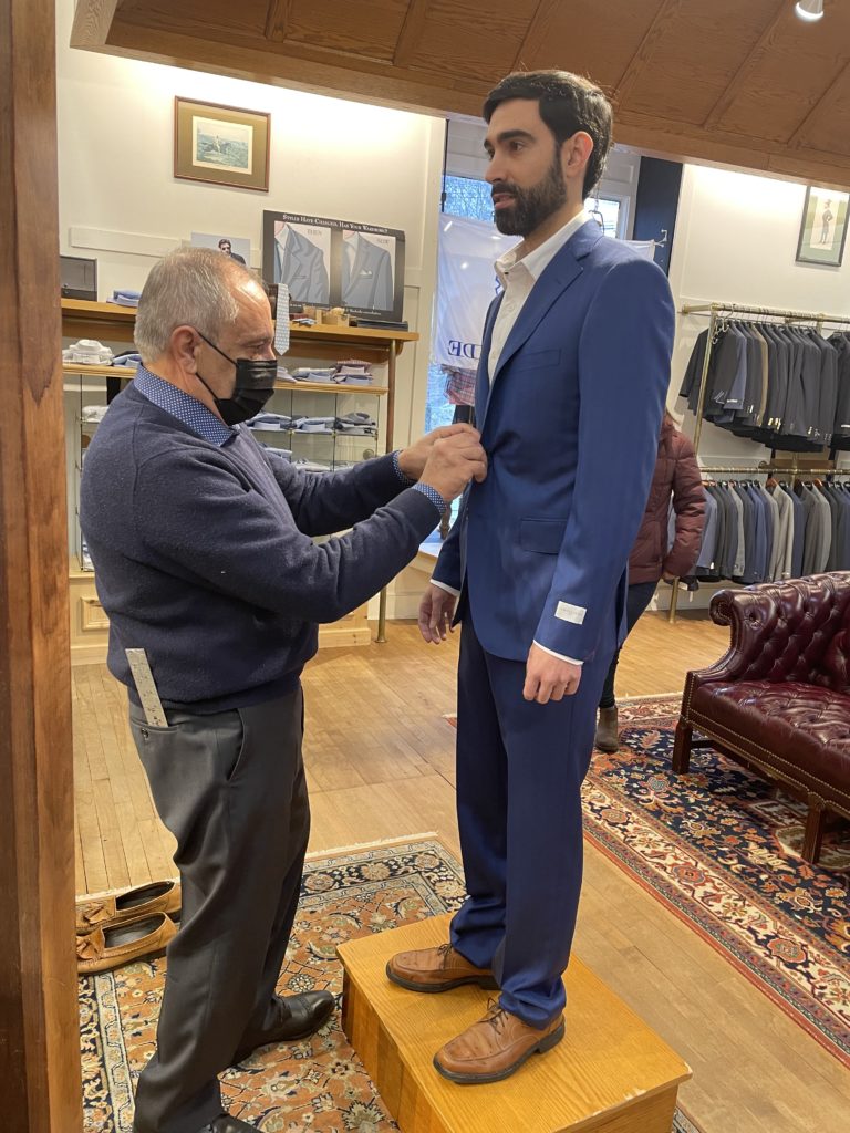 Tailor fitting customer's jacket for wedding suit