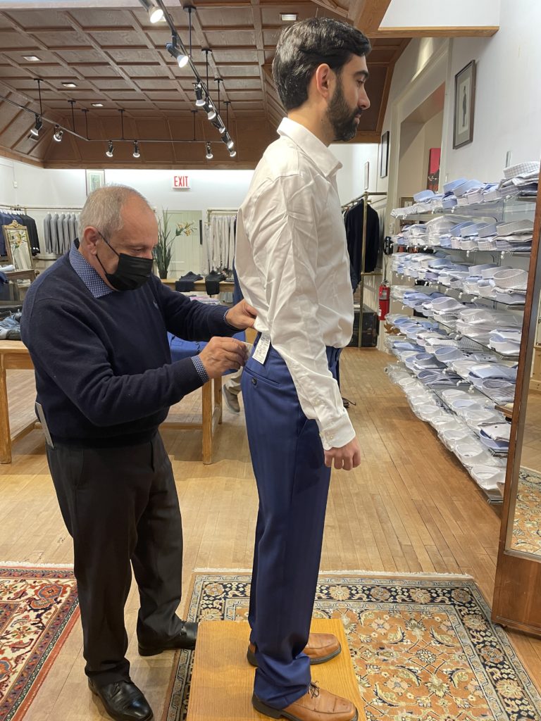 Tailor fitting customer's shirt for wedding suit