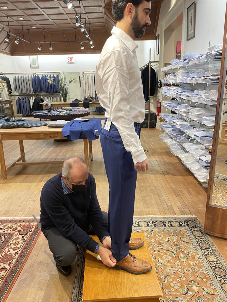 Tailor fitting customer's pants for wedding suit