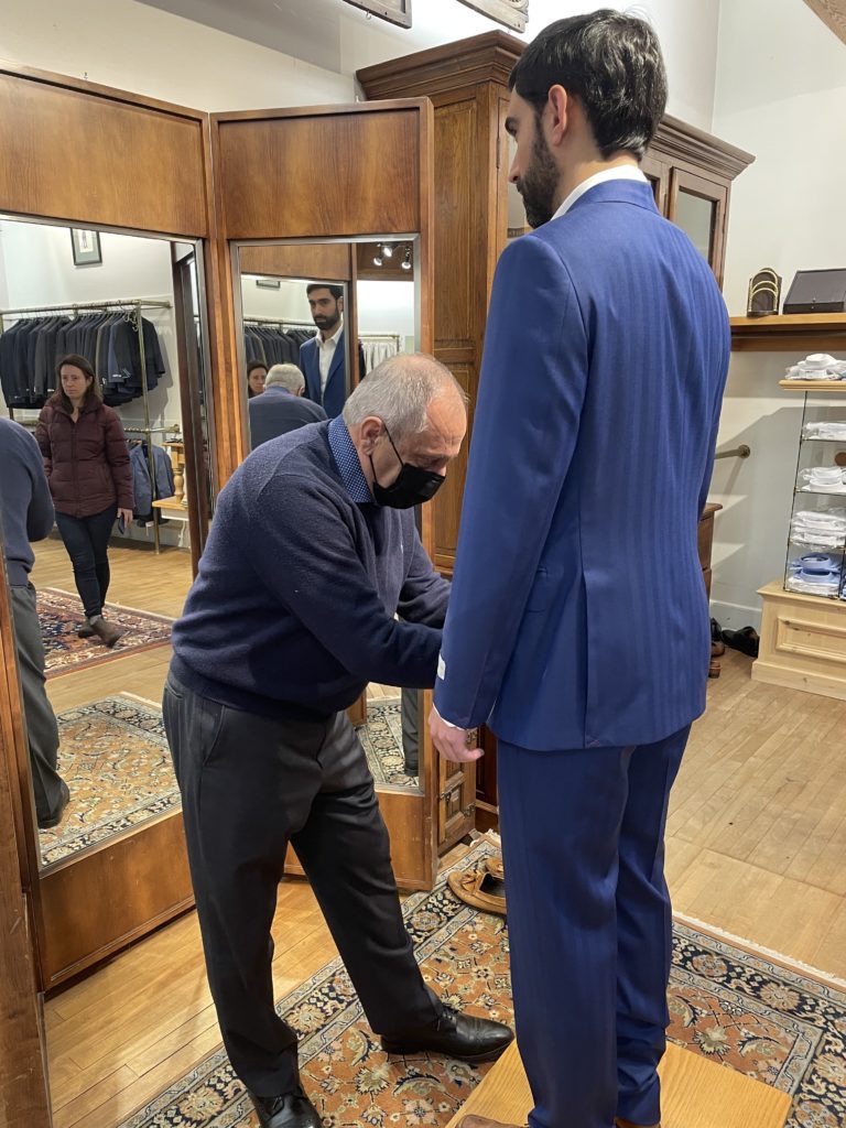 Tailor fitting wedding suit on customer