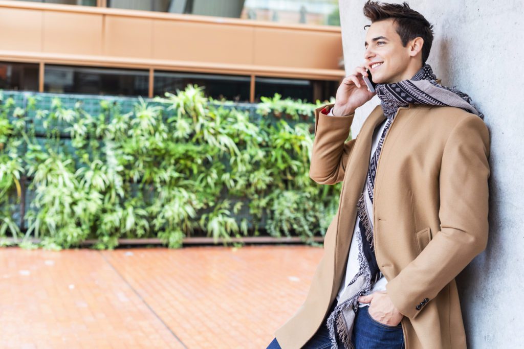 young-man-wearing-winter-clothes-while-using-a-mobile-phone-in-the-street