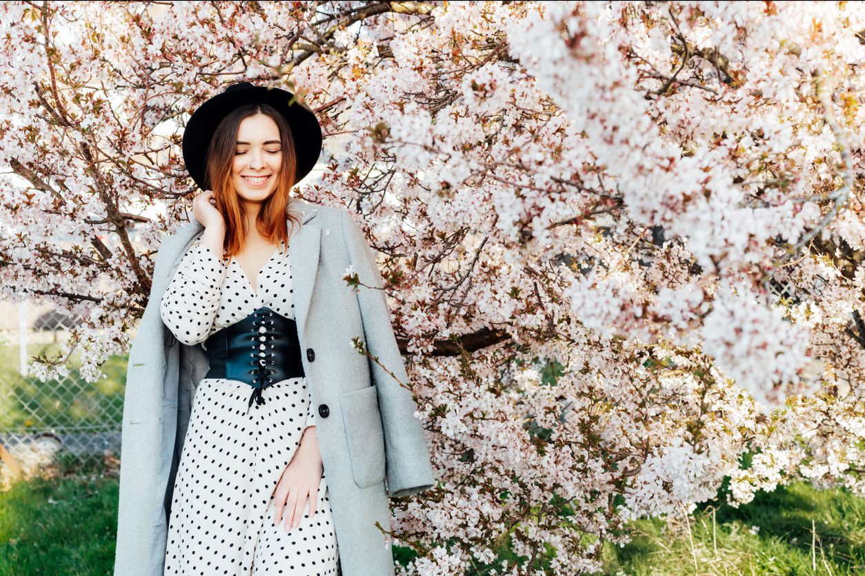 woman-with-closed-eyes-in-a-gray-trench-coat-and-hat-during-spring