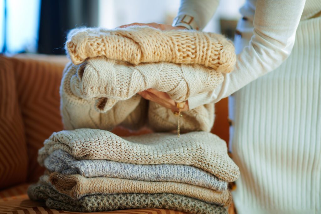 woman folding sweaters storing winter wardrobe