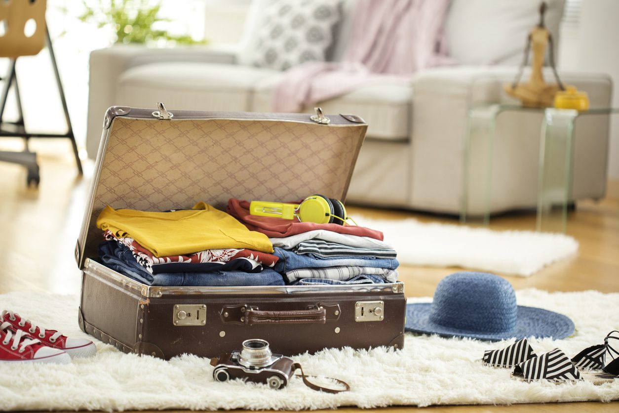 Packing single suitcase with clothes for a vacation capsule wardrobe.