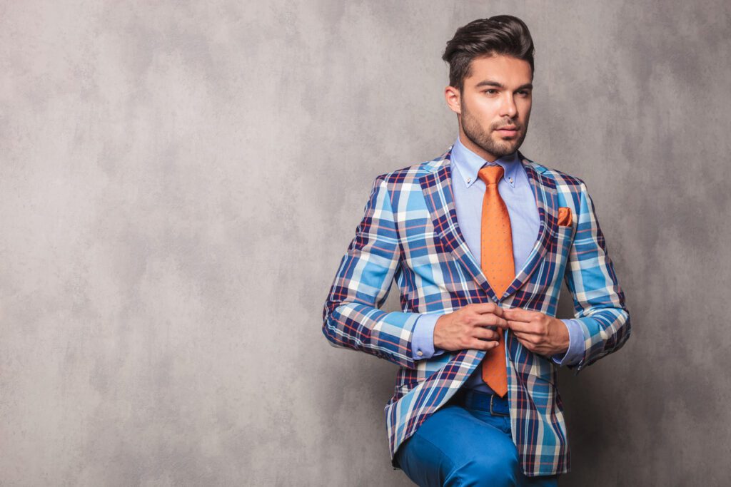 Young businessman looking away while closing his plaid blazer.