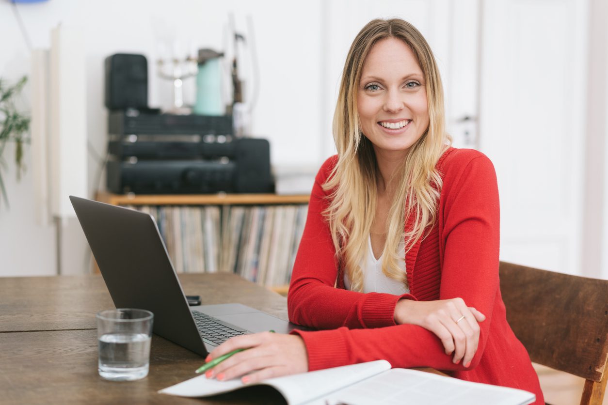 A woman wearing an office cardigan sitting in front of a laptop.