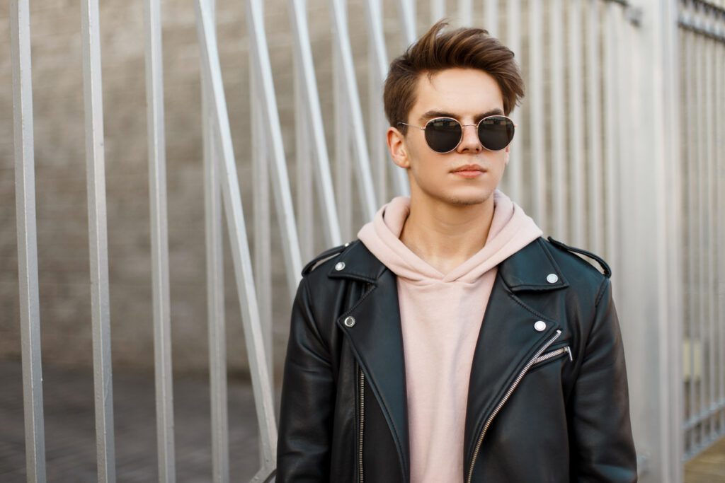 Young man wearing a leather jacket outdoors for fall fashion week.