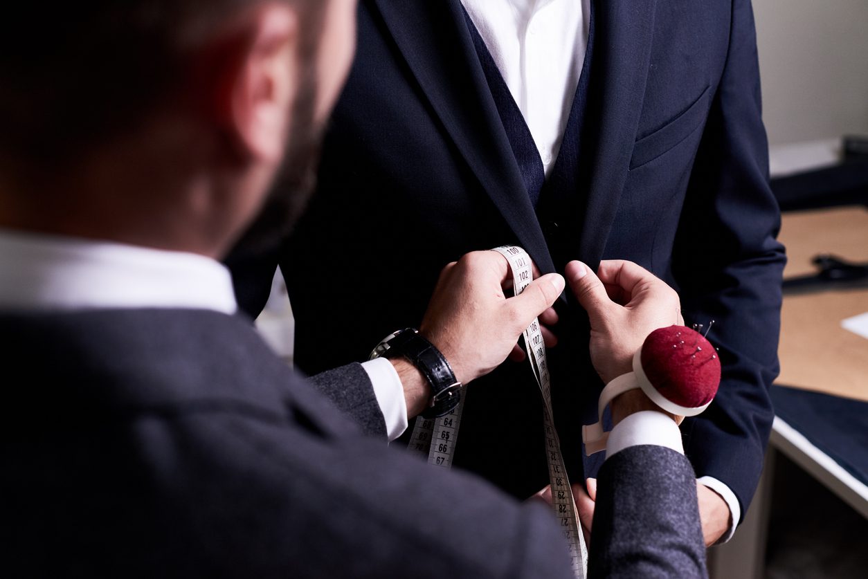 Tailor fitting a suit to a model after a weight change.