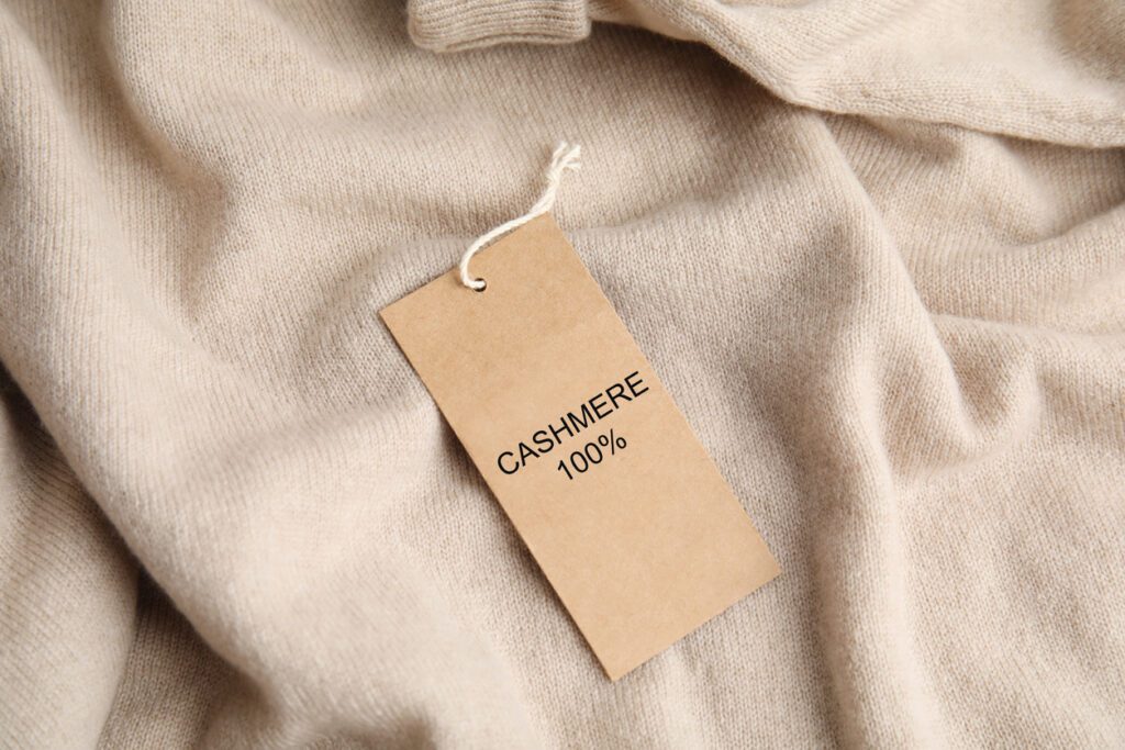Warm beige cashmere sweater with label to suggest the difference between high and low-quality cashmere.