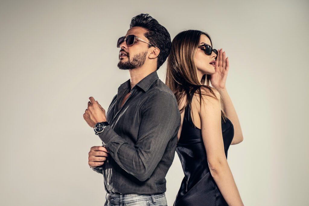 Young couple accessorizing their outfits with sunglasses.