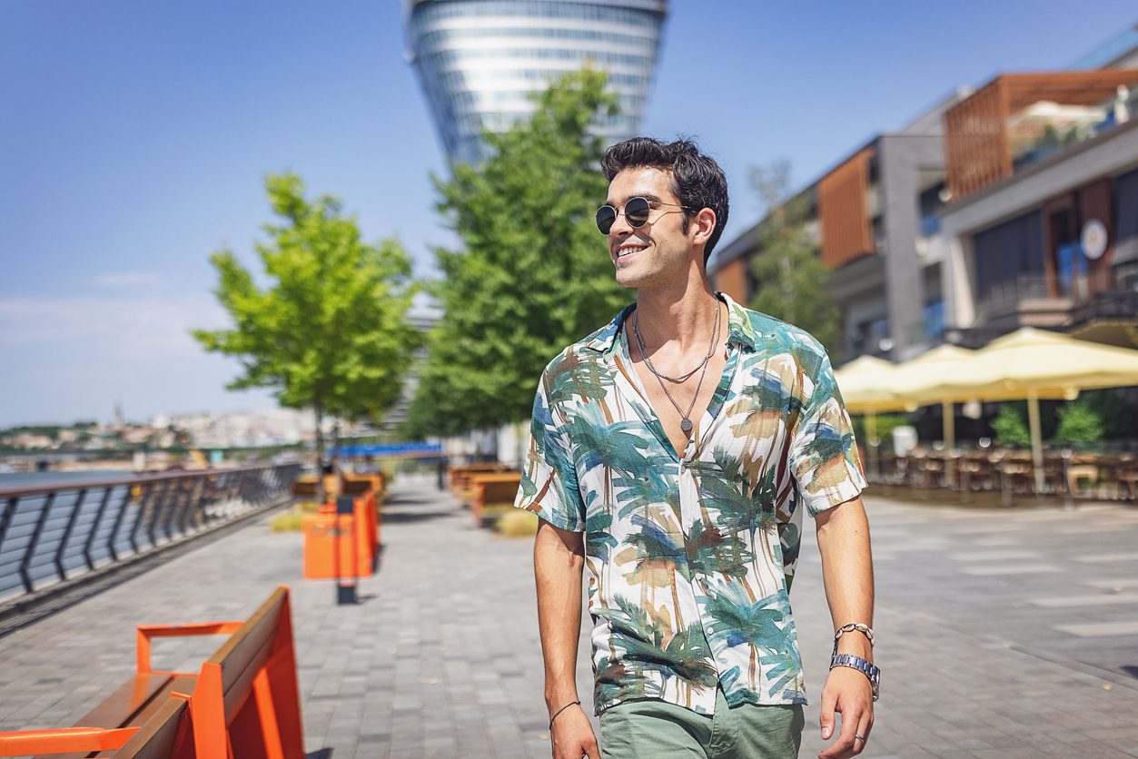 Man wearing a blouse with floral prints walking outdoors.