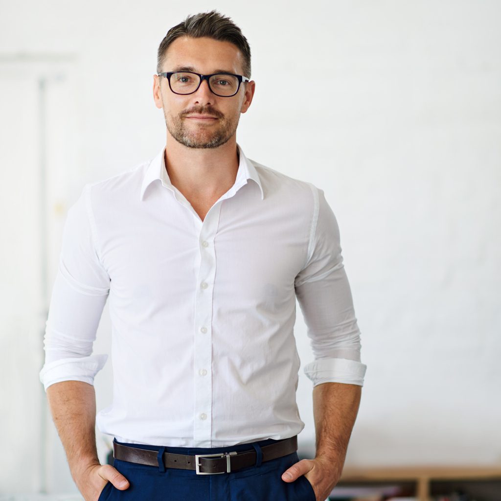 Businessman wearing a dress shirt, standing with his hands in his pockets.